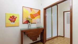 A hallway with a wooden console table, a vase with flowers, and two wall art pieces.