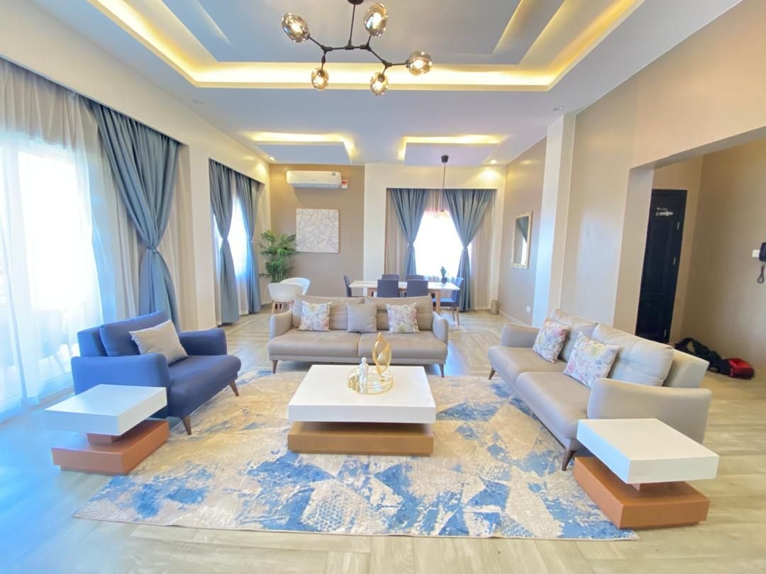 A modern living room with sofas, a coffee table, and a chandelier.