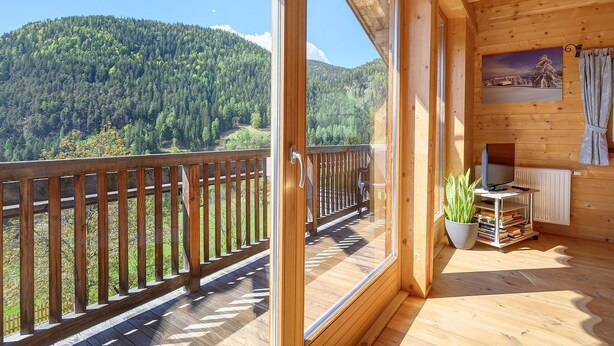 Eine Holzhütte mit Balkon, Fernseher und Bücherregal.