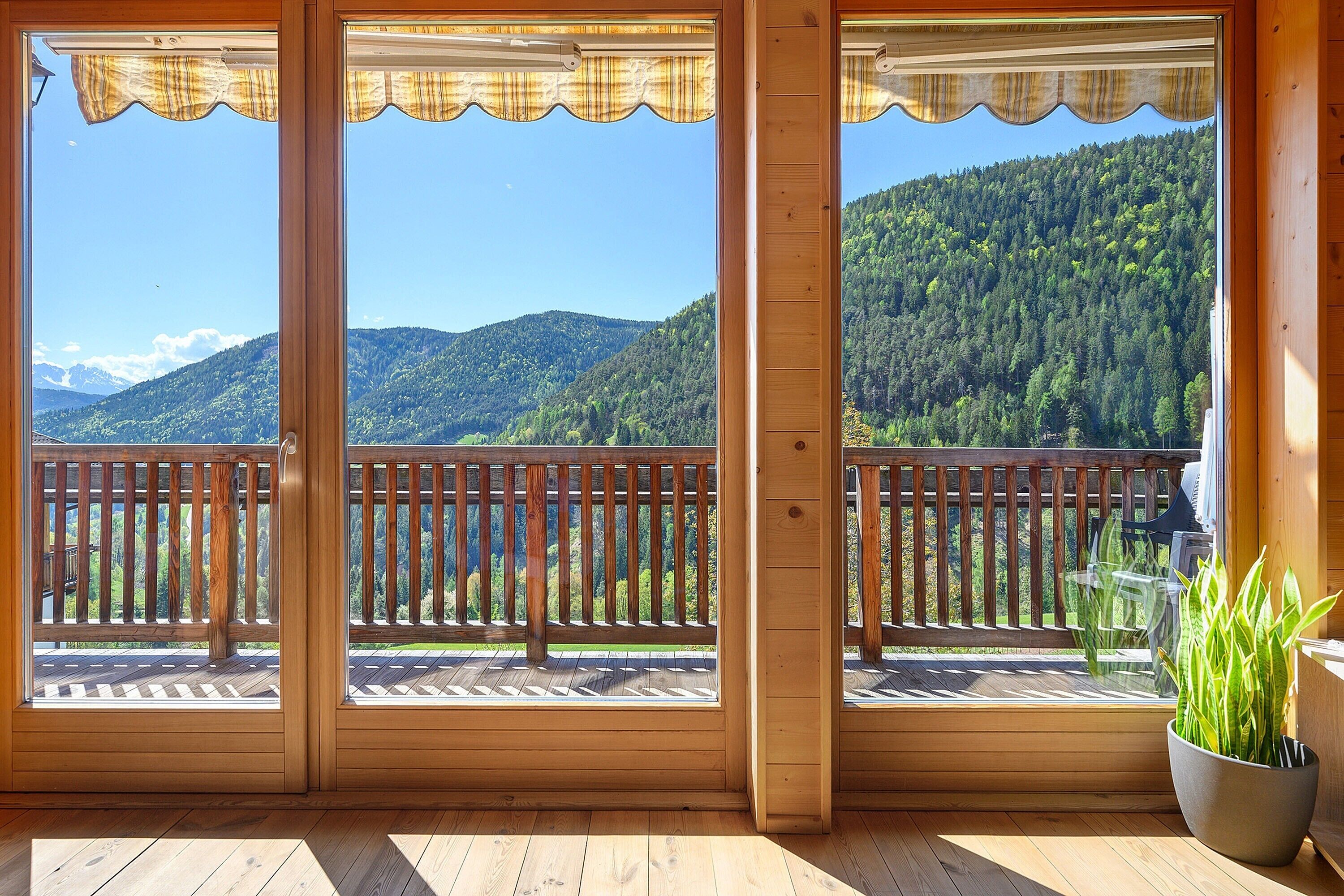 A wooden balcony with a view of a forested mountain.