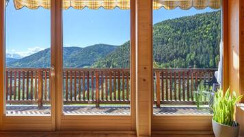 A wooden balcony with a view of a forested mountain.