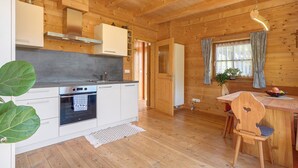 Ein Holzblock-Interieur mit Küche, Essbereich und einer sichtbaren Tür zu einem anderen Raum.