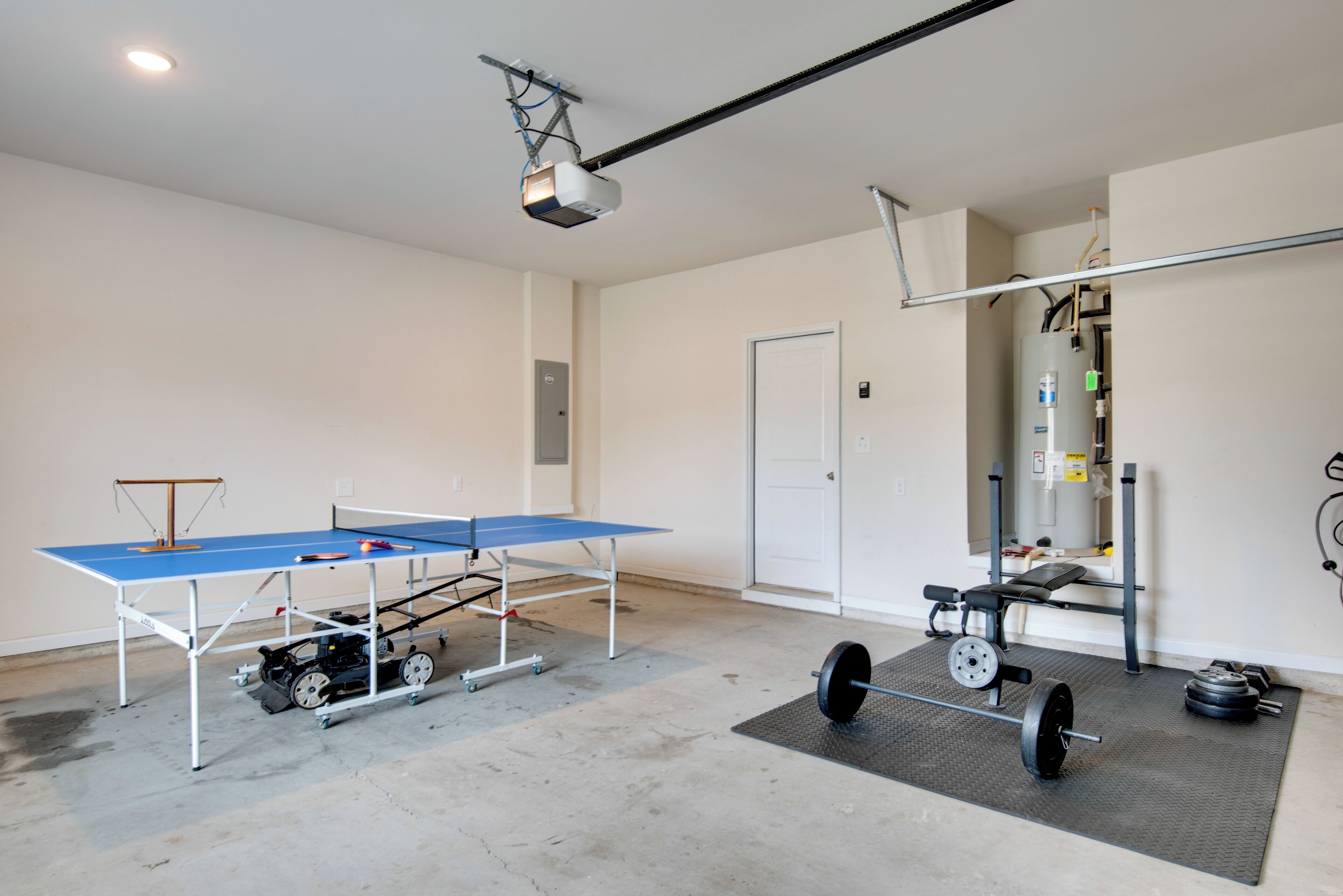 A room with a ping pong table, a weight bench, and a projector.