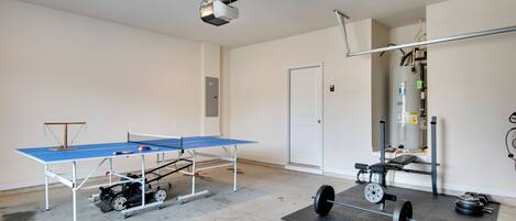 A room with a ping pong table, a weight bench, and a projector.