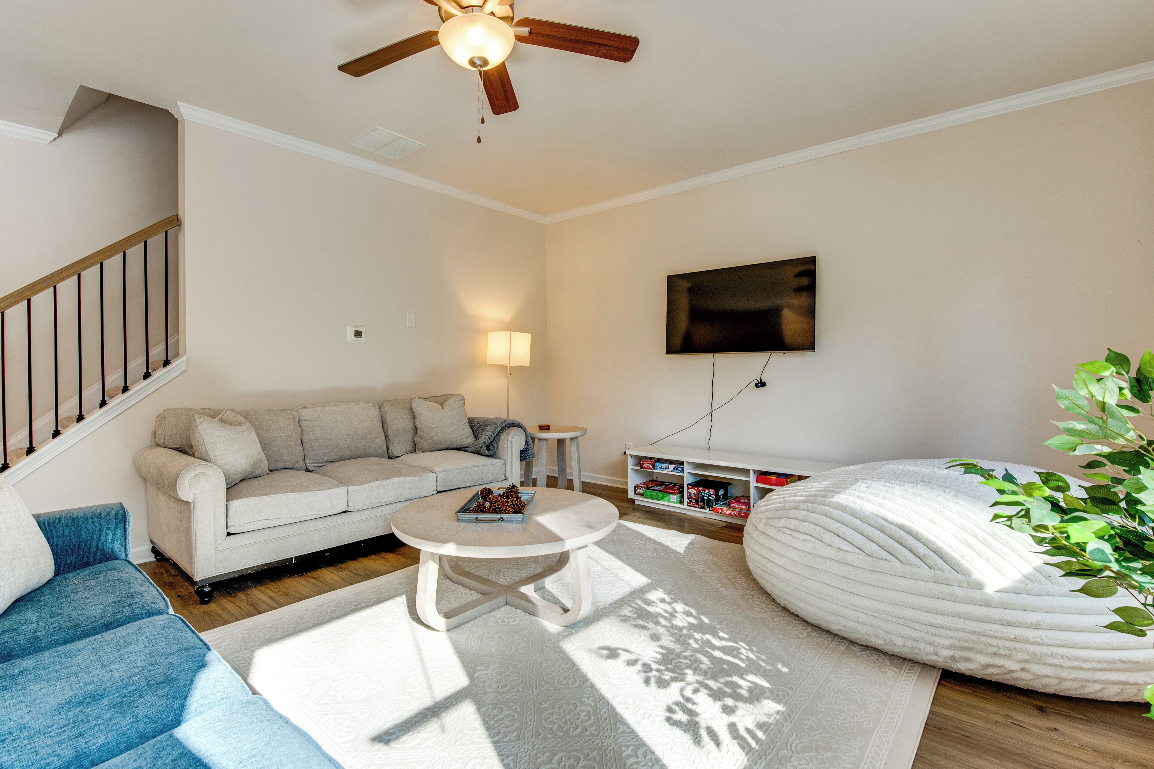 A living room with a sofa, a coffee table, a TV, a ceiling fan, and a bookshelf.