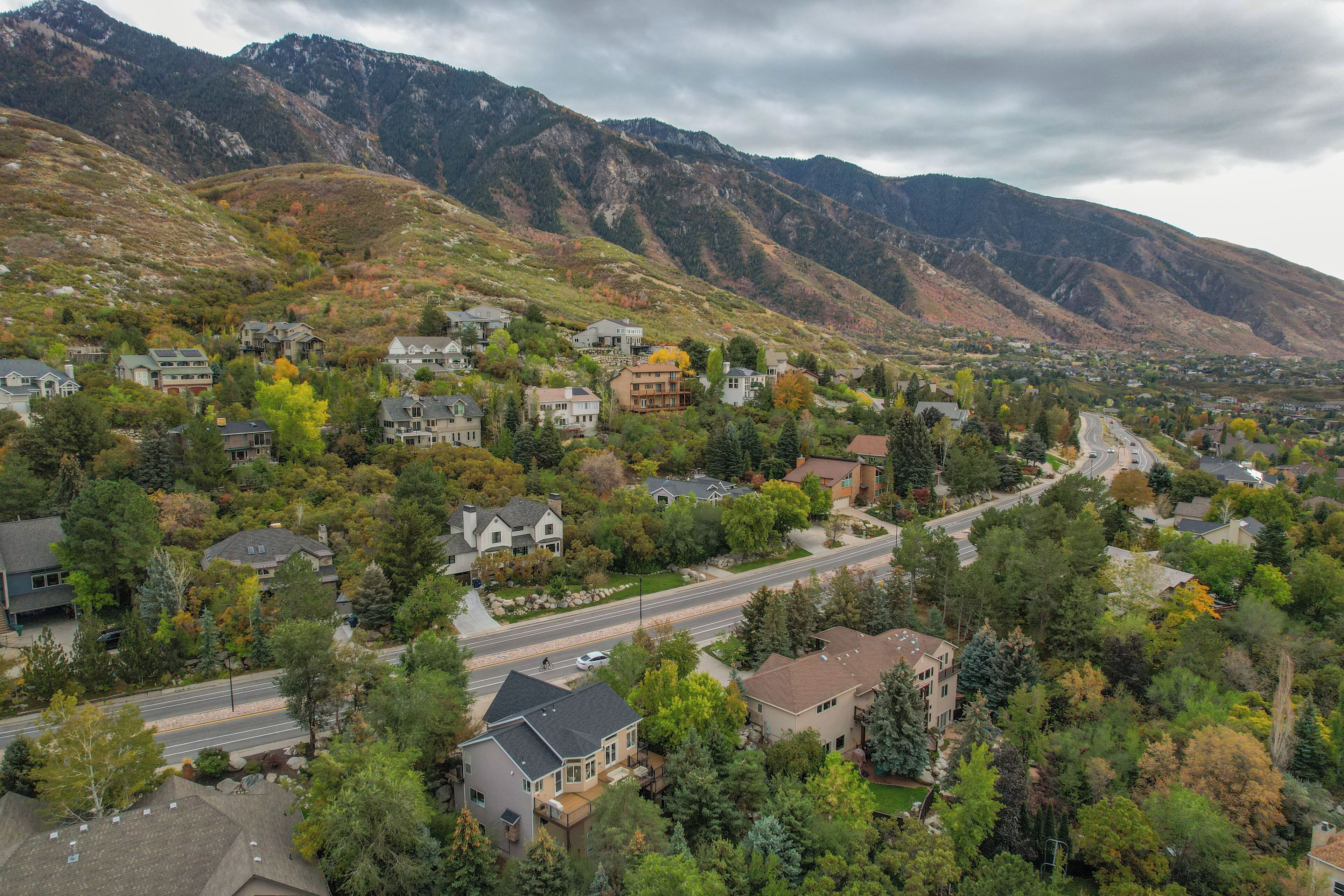A residential area with houses, a winding road, and mountains in the background.