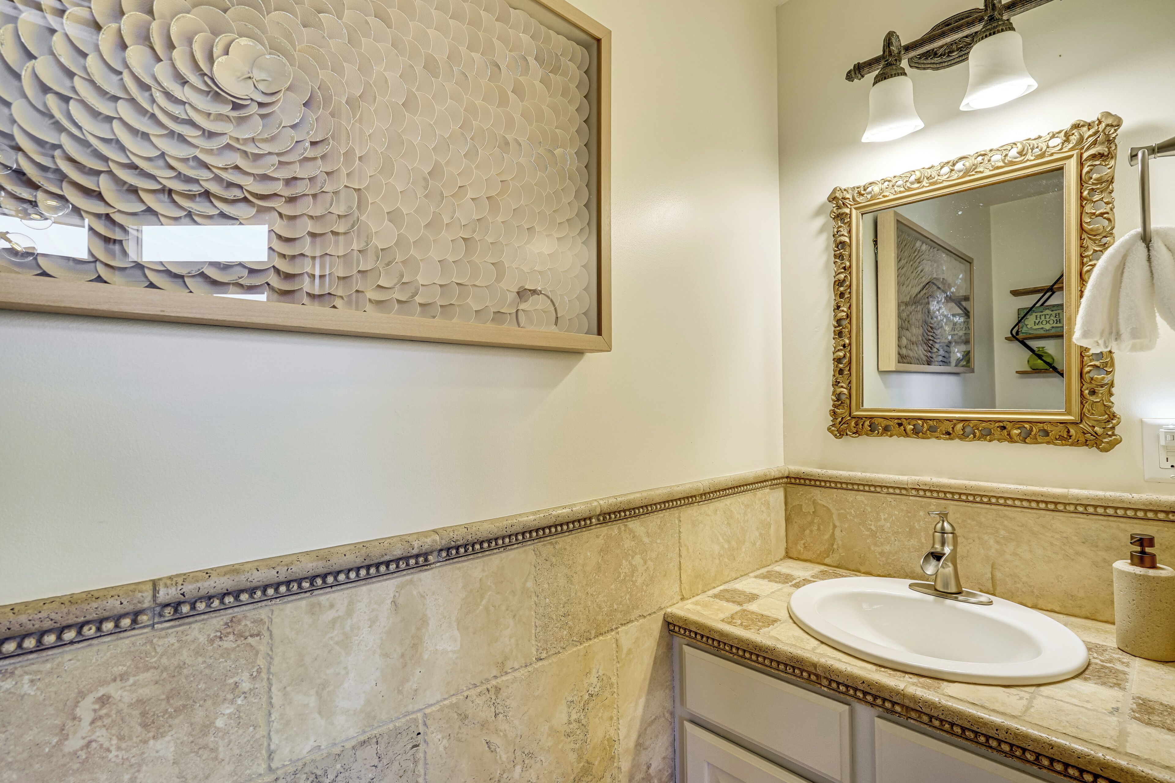 Un baño con lavamanos, espejo y un panel decorativo en la pared.