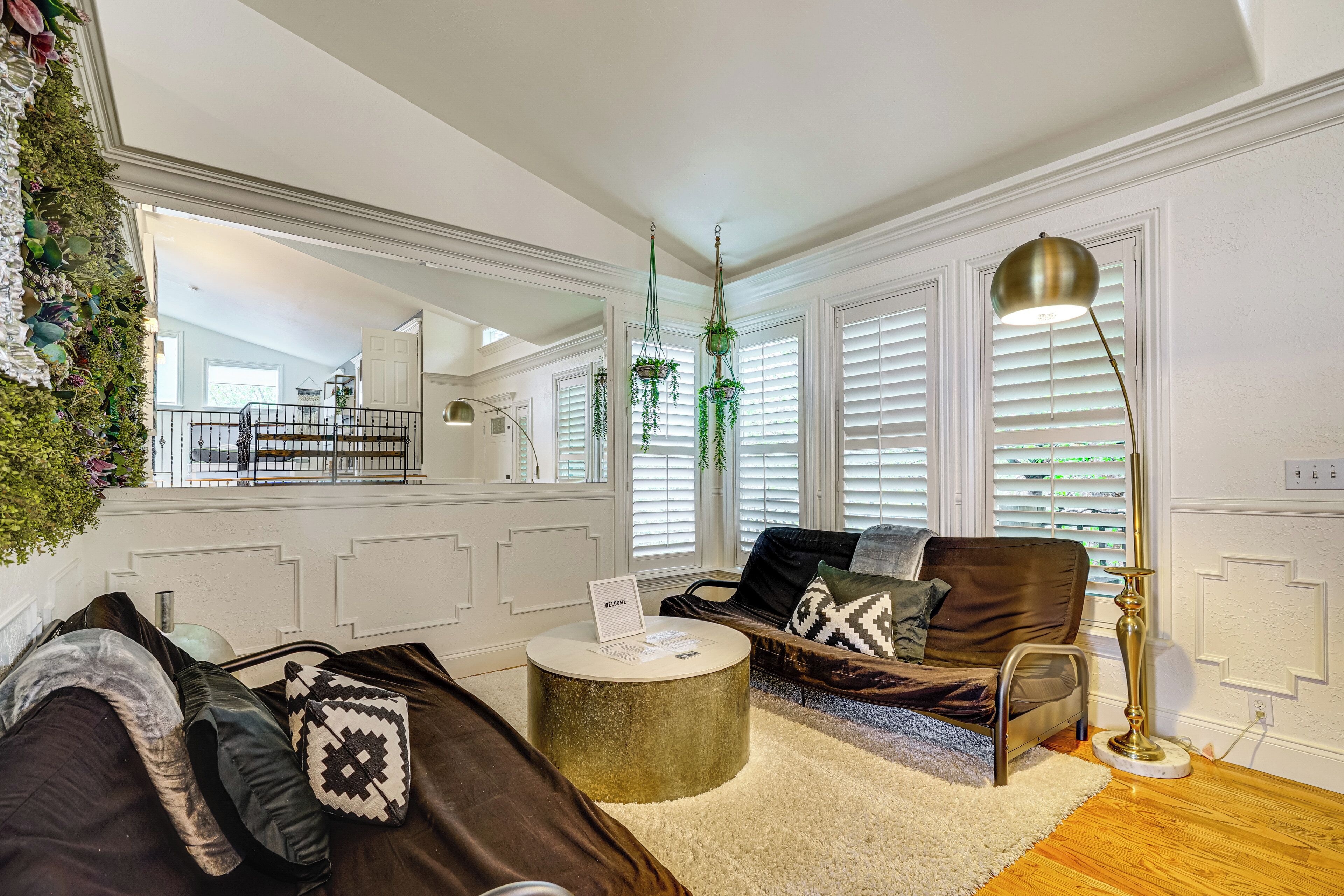 A living room with a brown sofa, a round coffee table, a floor lamp, and a hanging plant.