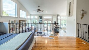 A spacious room with a large bed, wooden flooring, a balcony with a railing, and a ceiling fan. - Ski, Hike & Bike: 4,000 Sq Ft Bell Canyon Retreat (Sandy)