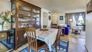A dining area with a wooden cabinet, chairs, a table with a tablecloth, and a chandelier. - 55-plus Community w/ Pool! Snowbird Escape in Mesa (Mesa)