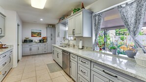 A kitchen with white cabinets, a dishwasher, a microwave, and a window with patterned curtains. - 55-plus Community w/ Pool! Snowbird Escape in Mesa (Mesa)