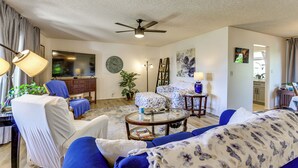 A living room with a ceiling fan, a flat-screen TV, a clock, and a sofa. - 55-plus Community w/ Pool! Snowbird Escape in Mesa (Mesa)