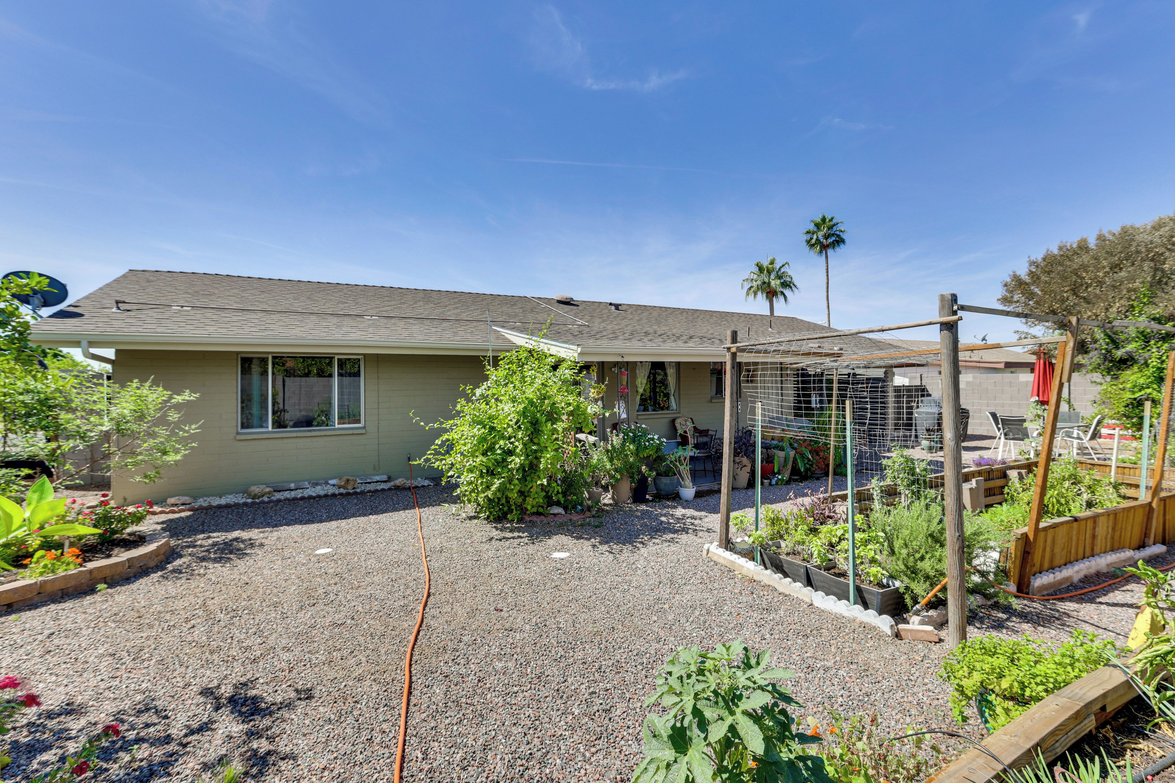 A residential house with a gravel driveway, a fenced garden area, and a wooden deck.