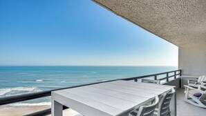 A balcony with a view of the ocean, a white table, and white chairs. - Beach, Pool & Sauna Access! Daytona Shores Escape (Daytona Beach Shores)