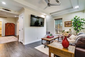 A living room with a sofa, coffee table, TV, and a plant. - Ultimate Stockyards Base! Home w/ Bonus Apartment (Fort Worth)