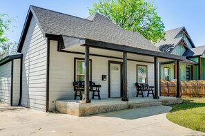 A single-story building with a porch, two chairs, and a wooden fence. - Ultimate Stockyards Base! Home w/ Bonus Apartment (Fort Worth)