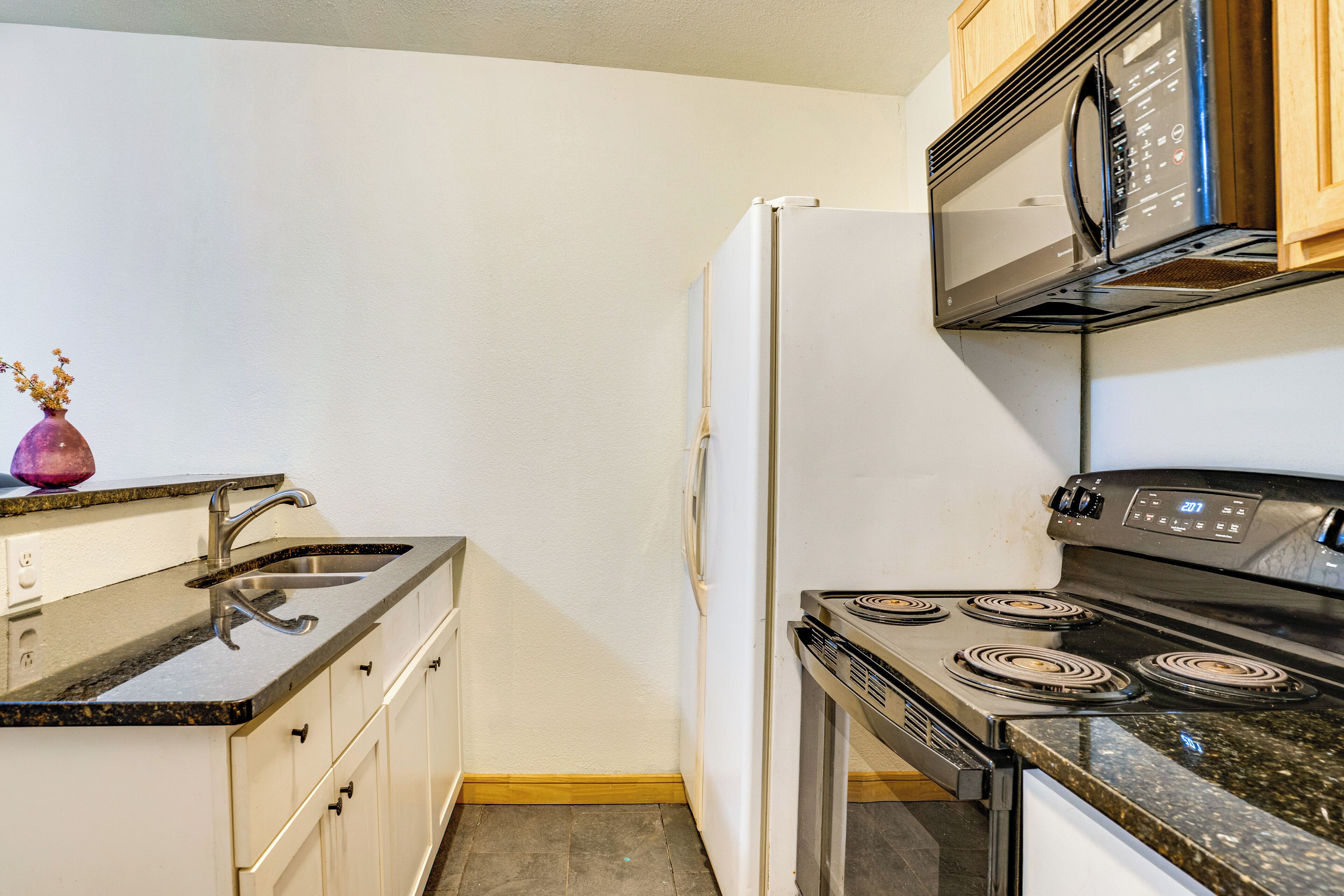 Una cocina equipada con fregadero, estufa, horno microondas y refrigerador.