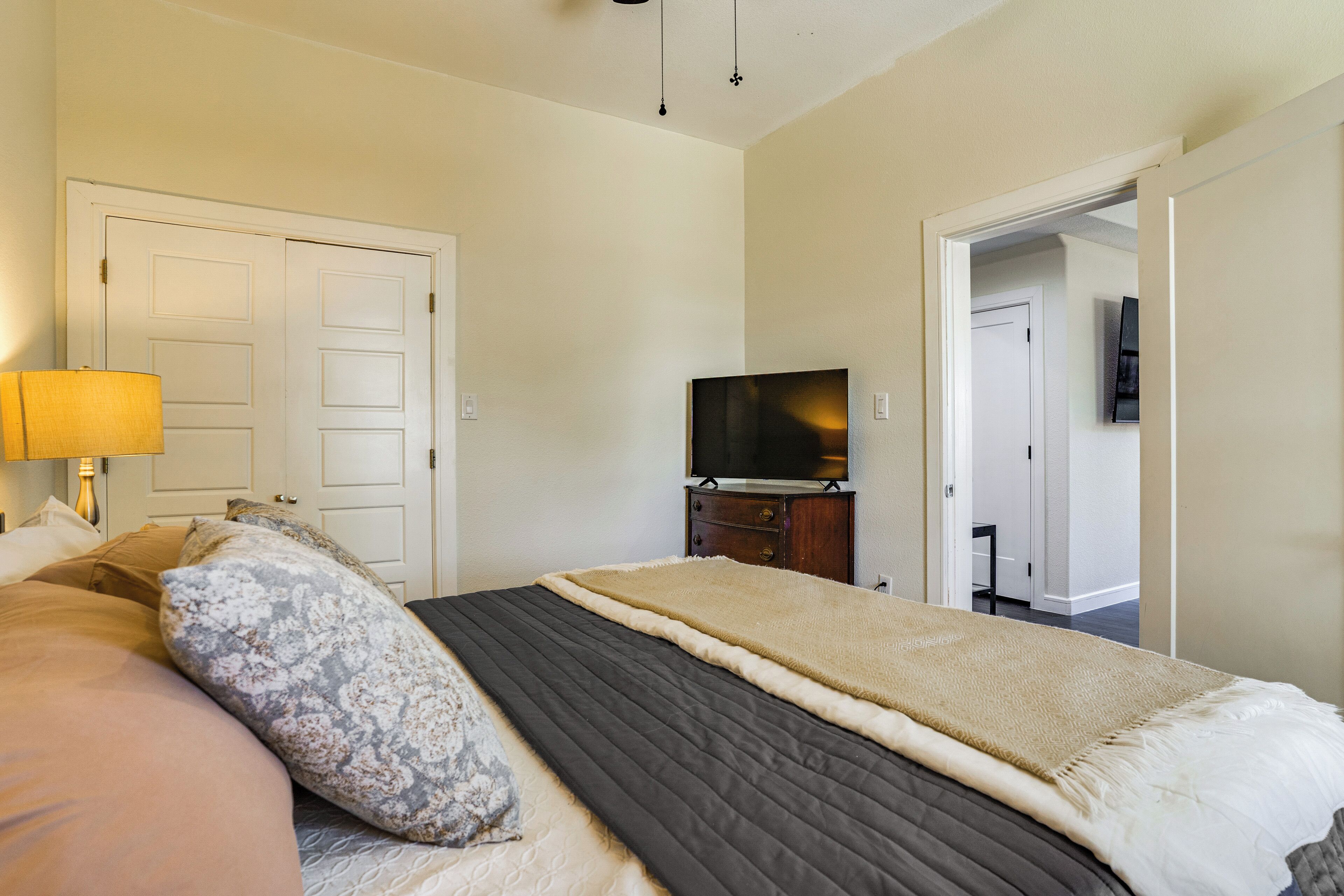 A bedroom with a bed, a television, and a door leading to another room.