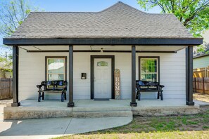 A small, single-story house with a porch, two benches, and a door with a 'HOME' sign. - Ultimate Stockyards Base! Home w/ Bonus Apartment (Fort Worth)