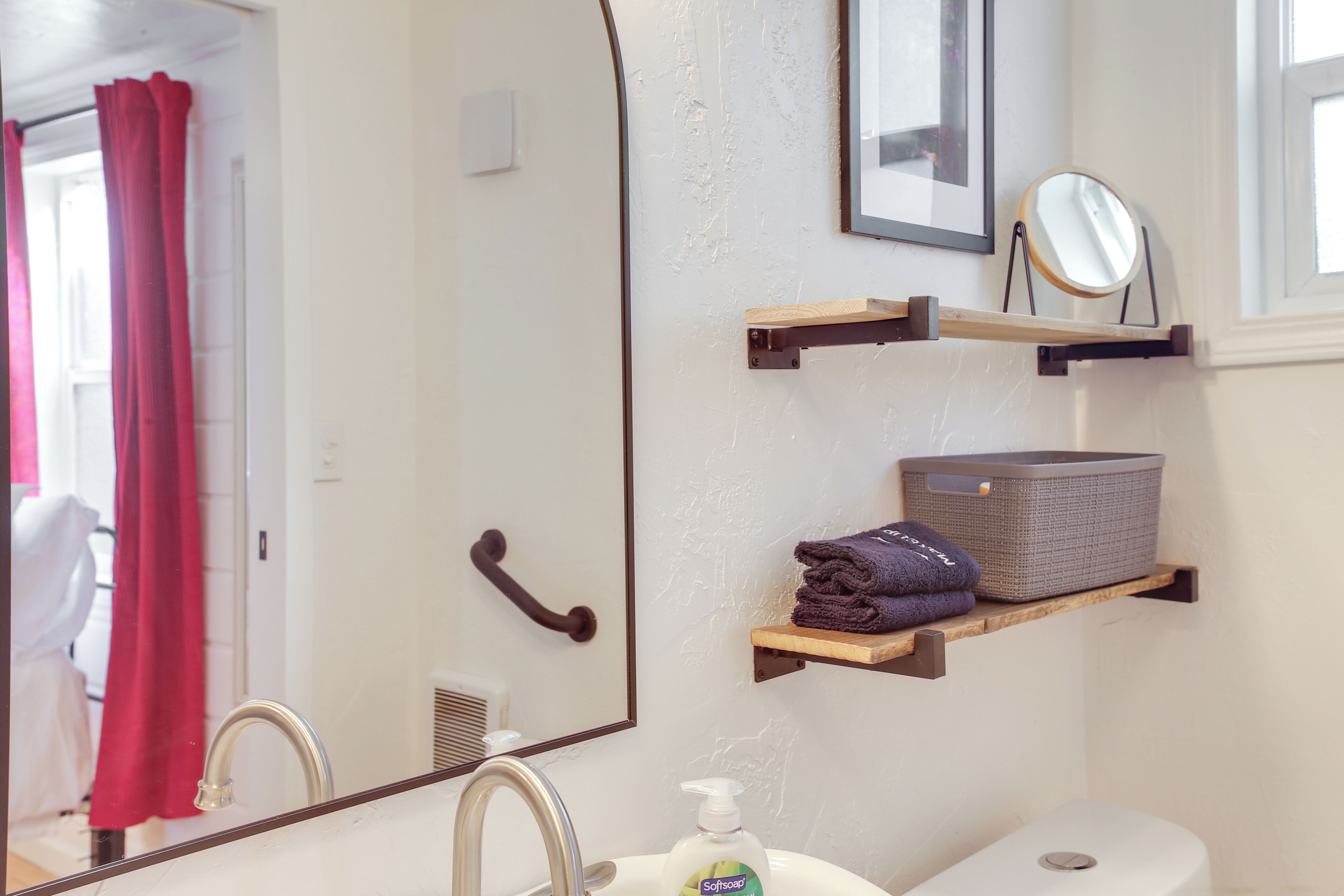 A bathroom with a mirror, sink, and towel rack.