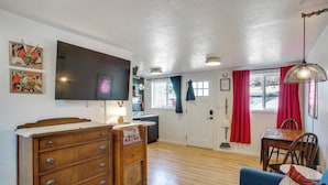 A living room with a TV, wooden dresser, blue sofa, and a dining area with a table and chairs. - Unit 2: Cozy 1-br, 3 Mi to Riverfront Park (Spokane)