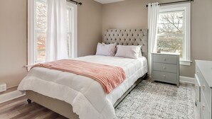 A bedroom with a bed, a nightstand, a dresser, and a window with curtains. - Free Parking! Townhome 3 Mi to Dtwn Rochester (Rochester)