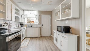 A kitchen with white cabinets, a microwave, and a window with curtains. - Free Parking! Townhome 3 Mi to Dtwn Rochester (Rochester)