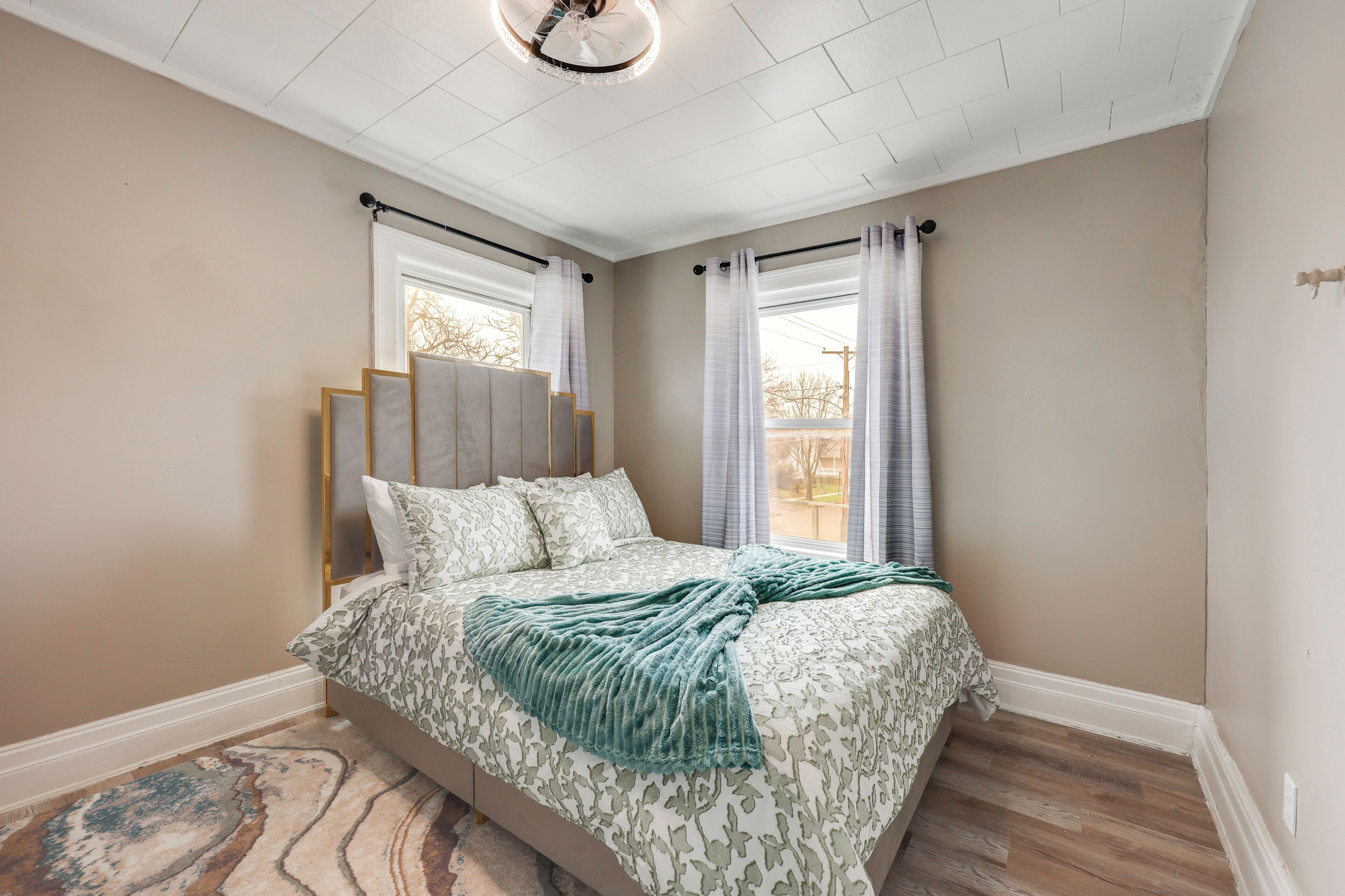 A bedroom with a bed, curtains, a ceiling fan, and a window.