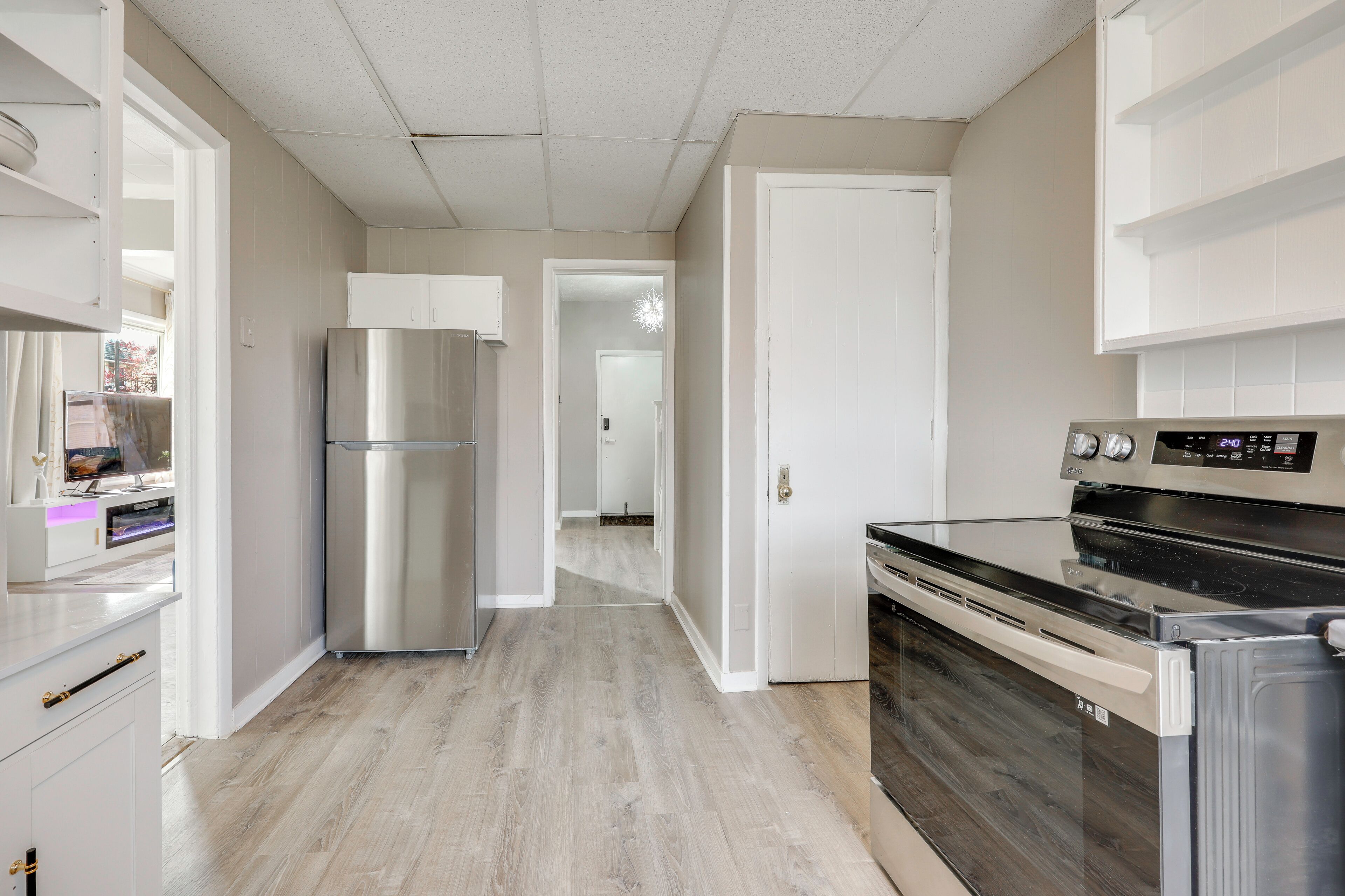 Una cucina moderna con elettrodomestici in acciaio inossidabile, pavimento in legno e mobili bianchi.