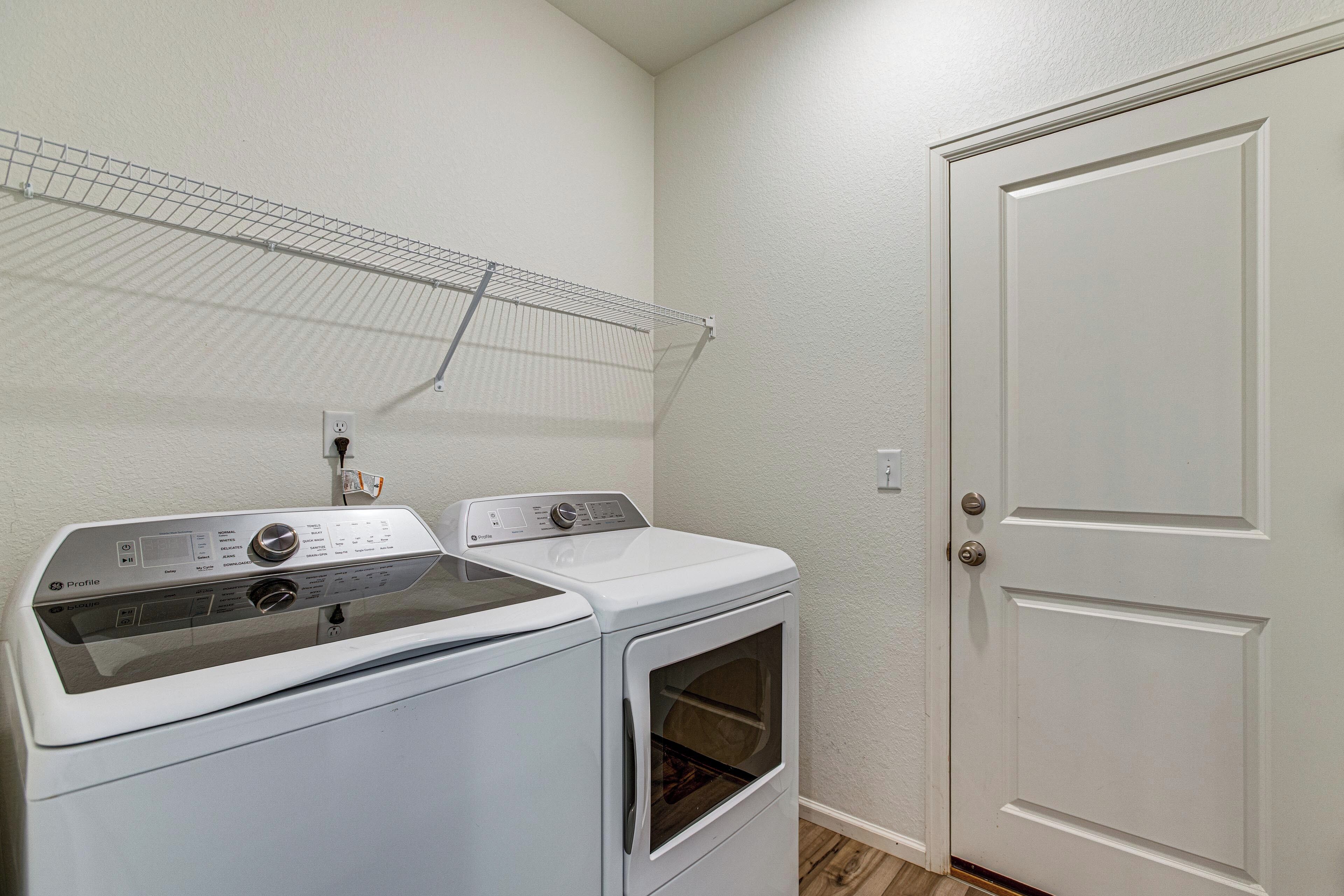 A laundry area with two stacked washers and dryers, a metal drying rack, and a white door.
