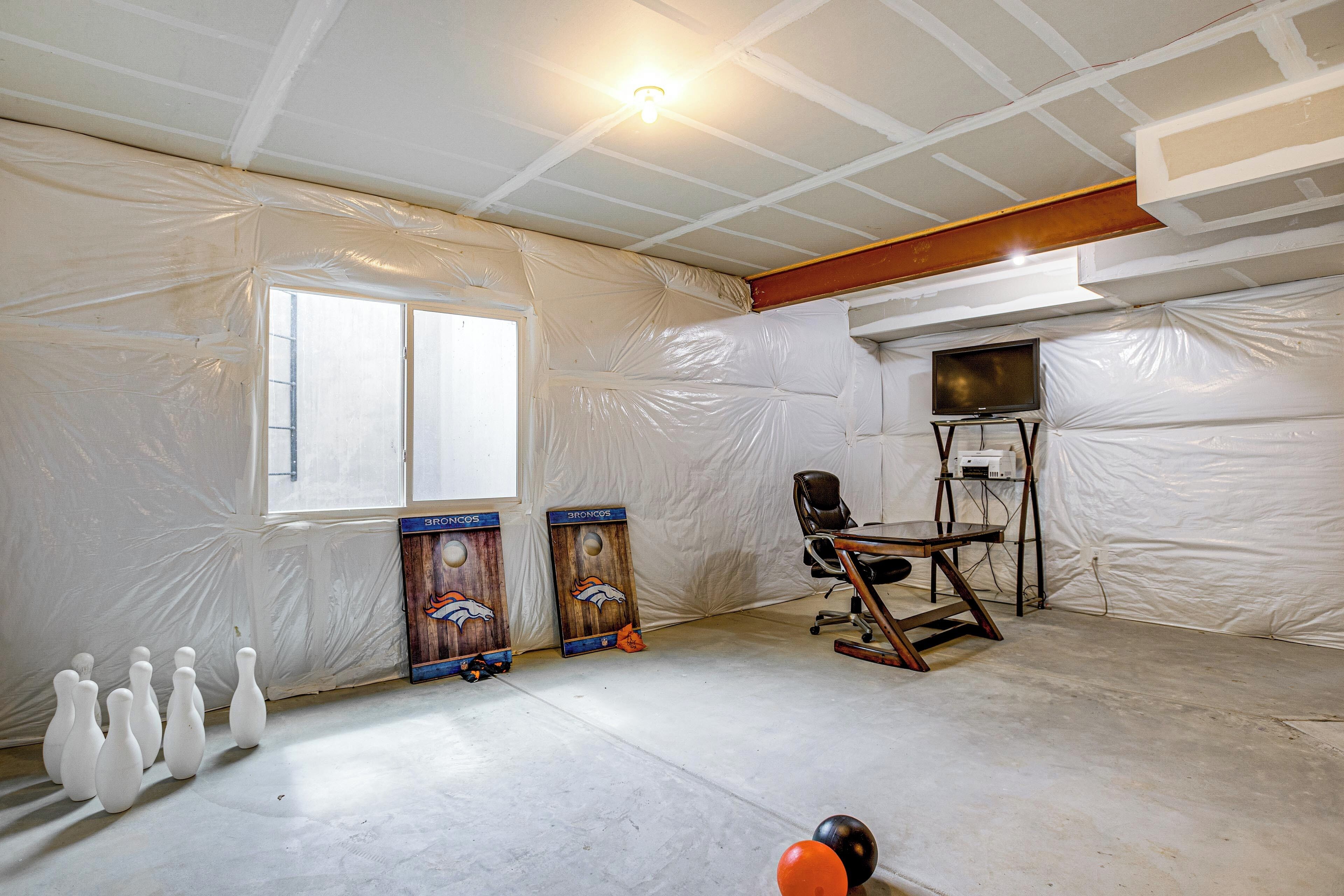 Una habitación con un ventanal grande, televisor, una zona de bolos y una silla.