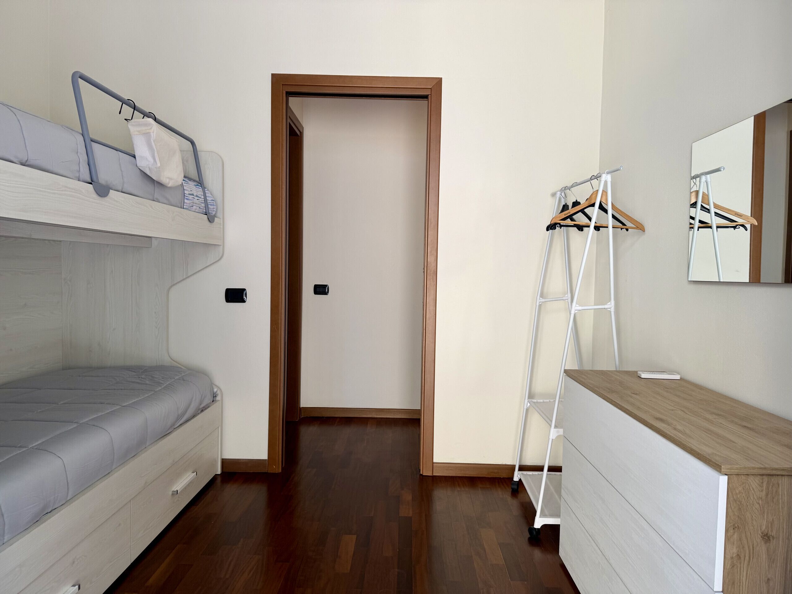 A room with a bunk bed, a dresser, a mirror, and a ladder.