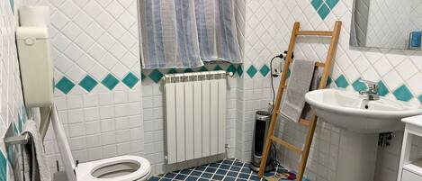 Et badeværelse med toilet, bidet, vask og en radiator.