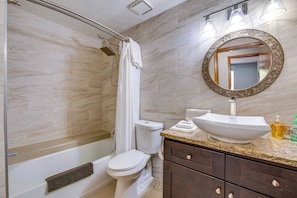 Un baño con ducha, inodoro, lavamanos y espejo.