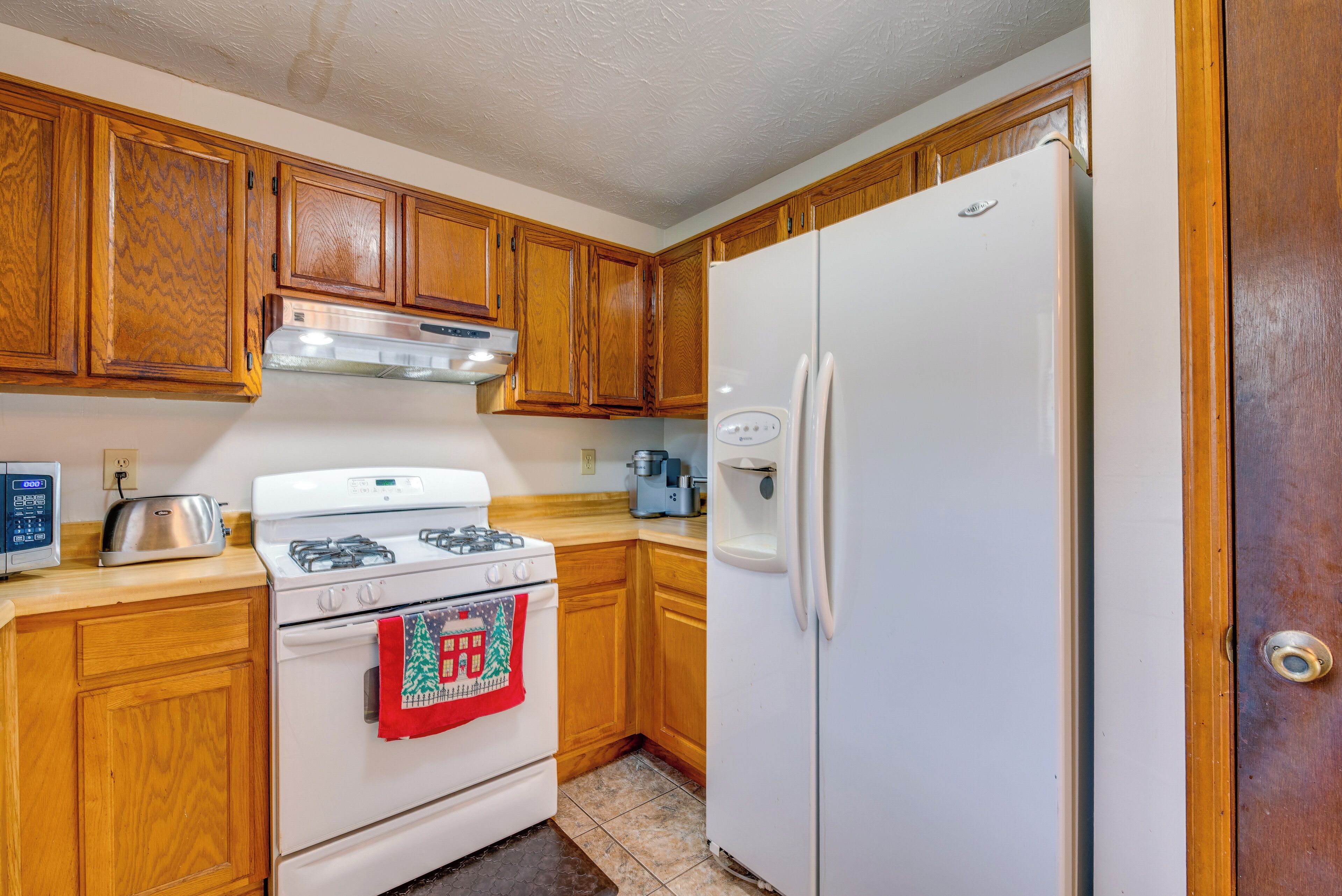 A kitchen with wooden cabinets, a white stove, a white refrigerator, and a toaster.