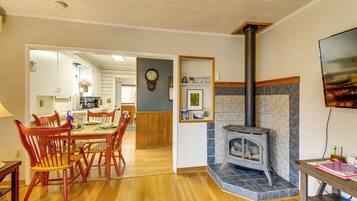 A dining area with wooden chairs, a table, and a fireplace.