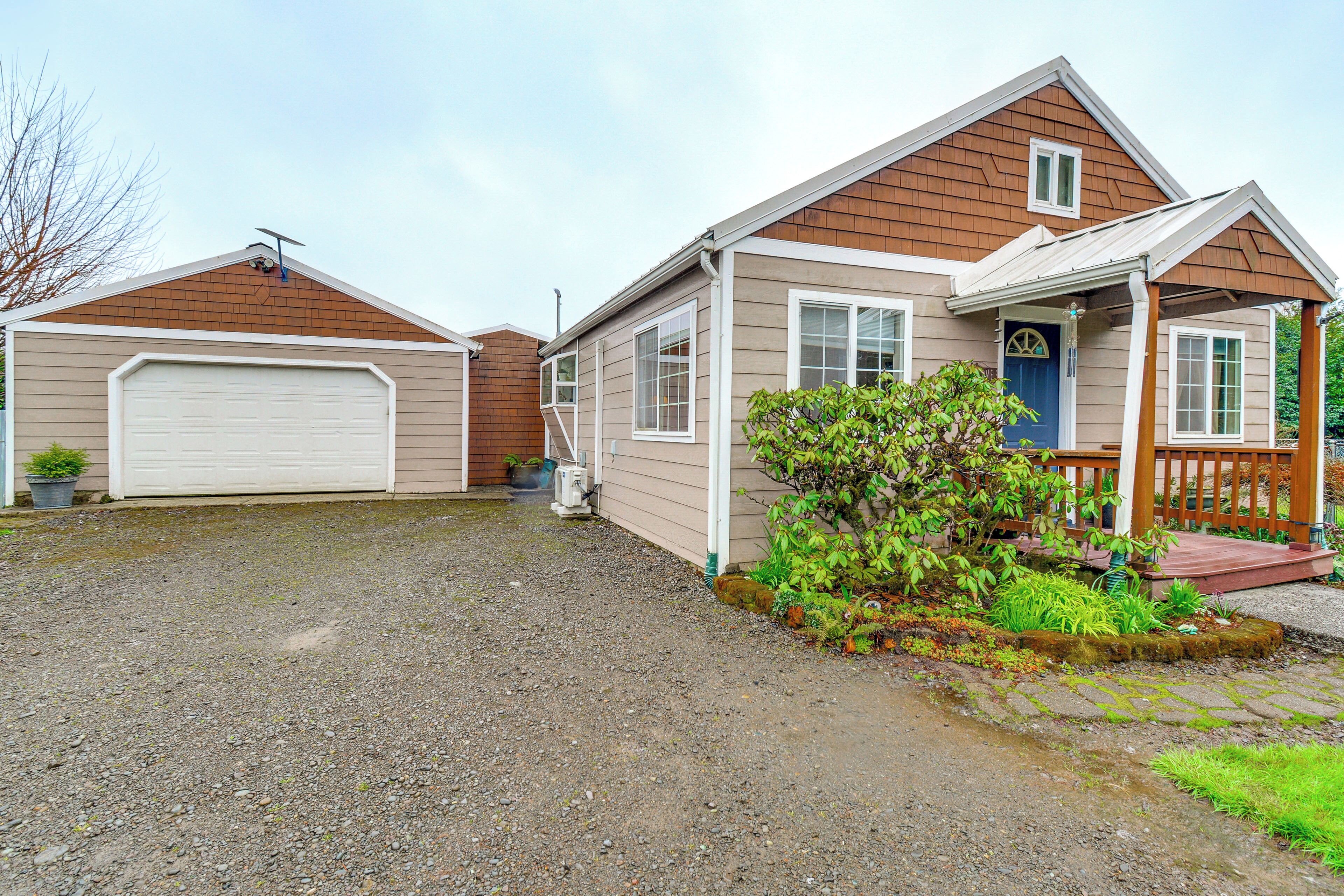 A two-story house with a garage, a front porch, and a small garden.