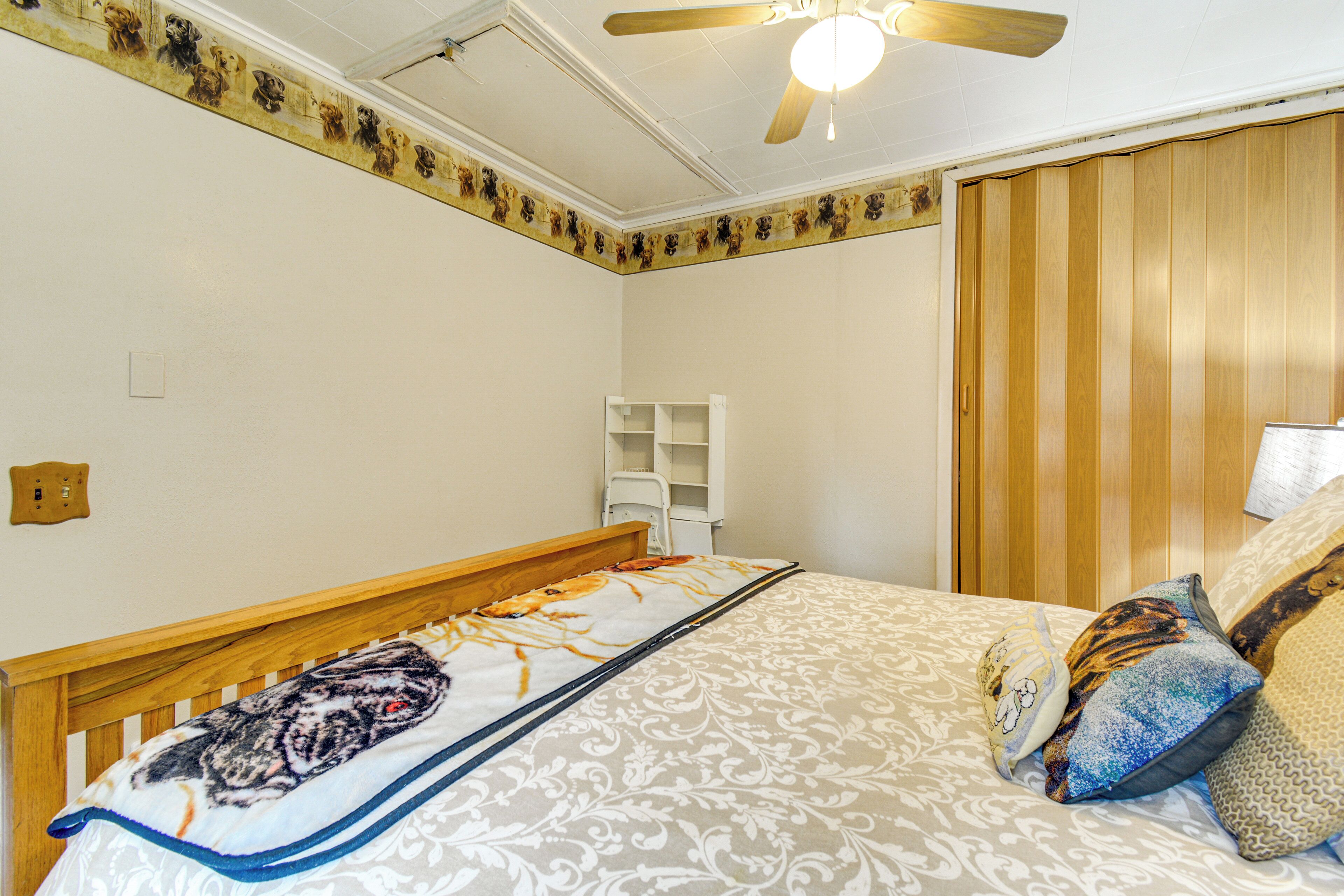 A bedroom with a wooden bed, a ceiling fan, and a wall-mounted shelf.