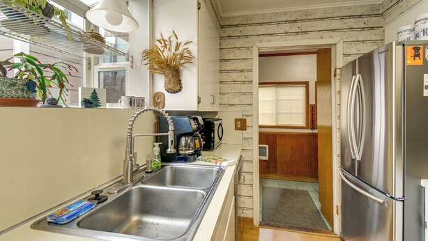 Una cocina con un lavamanos de acero inoxidable, una cafetera y un refrigerador.