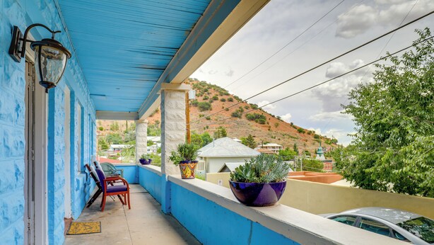 A balcony with blue walls, a red chair, and potted plants. - Walkable Group Getaway in Bisbee: 4-unit Bundle! (Bisbee)