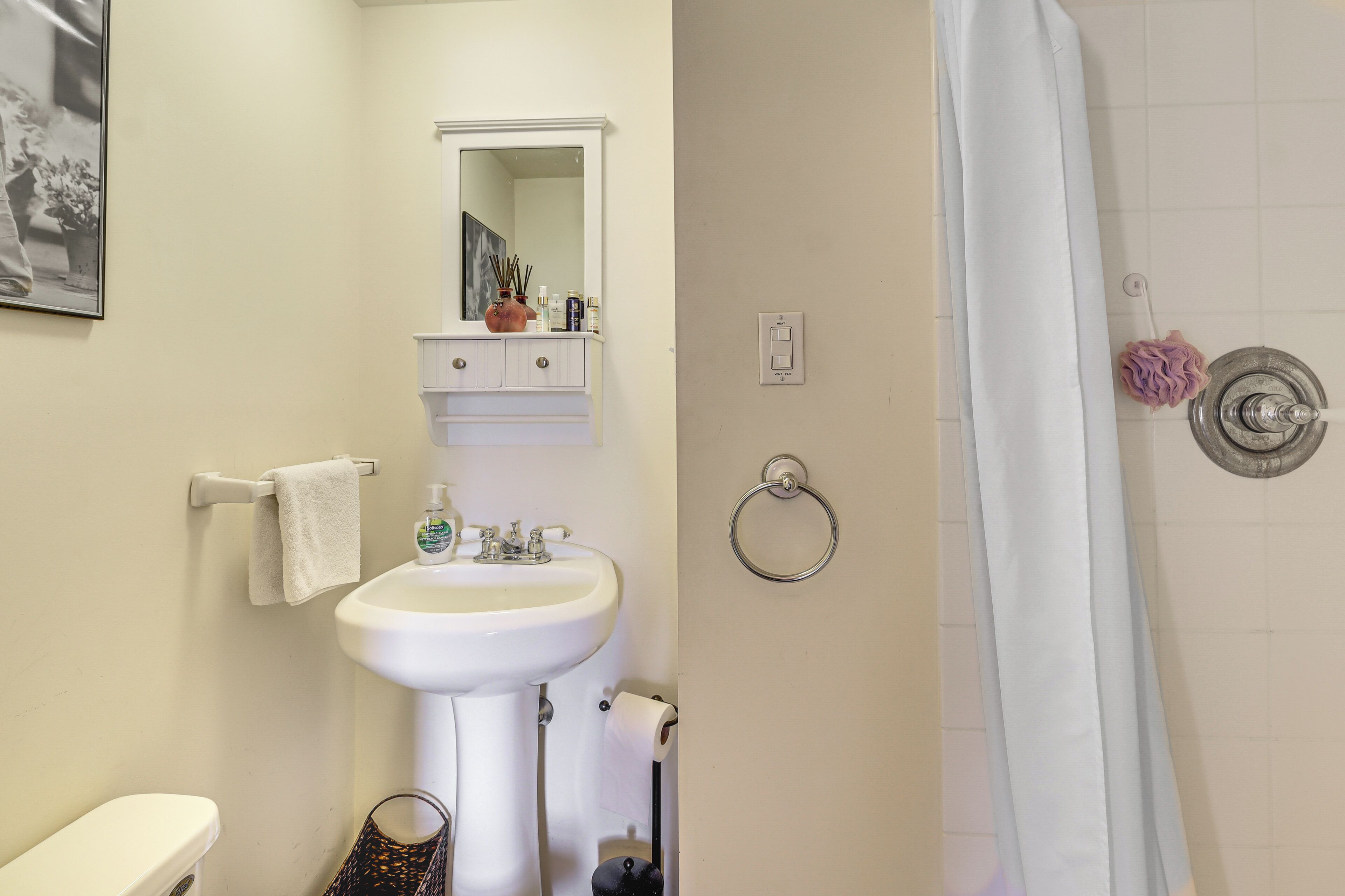 A bathroom with a sink, mirror, towel rack, toilet, and shower curtain.