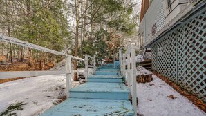 A staircase leading up to a house with a white fence and snow on the ground.