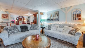 A living room with two patterned sofas, a coffee table, and a large window with curtains.