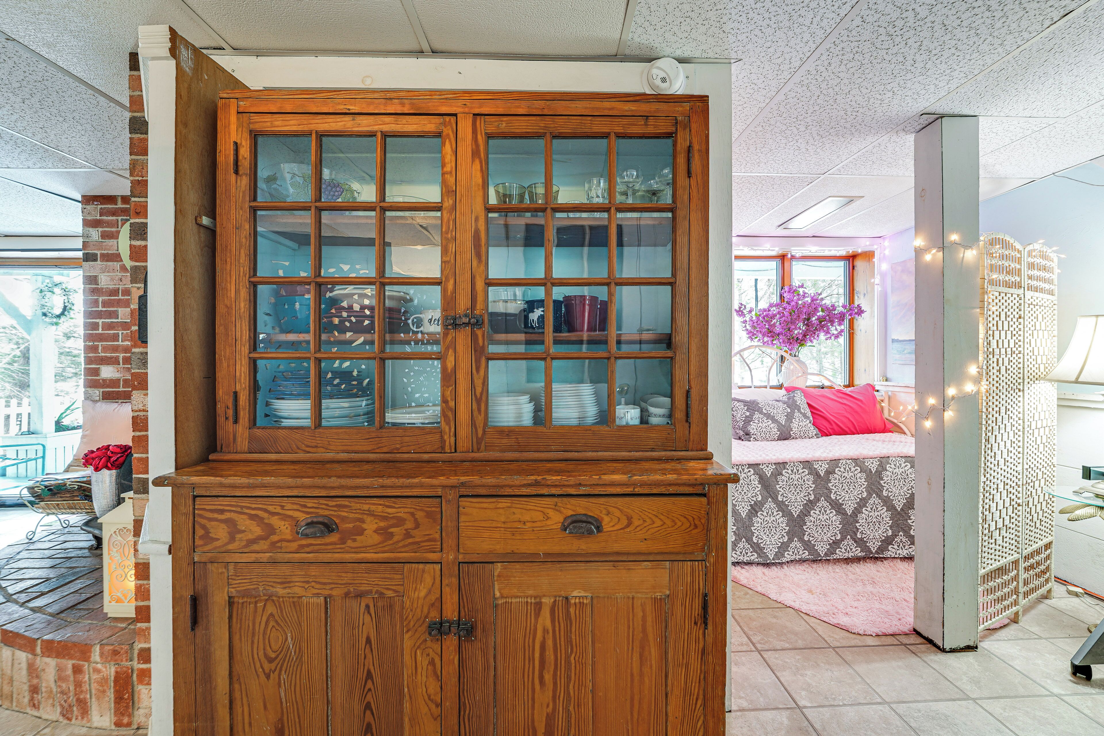 Een houten kast met glazen deuren, een bakstenen muur en een gestreept bankje.