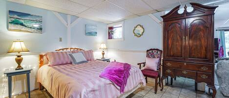 A bedroom with a bed, bedside tables, a dresser, a chair, and artwork on the walls.