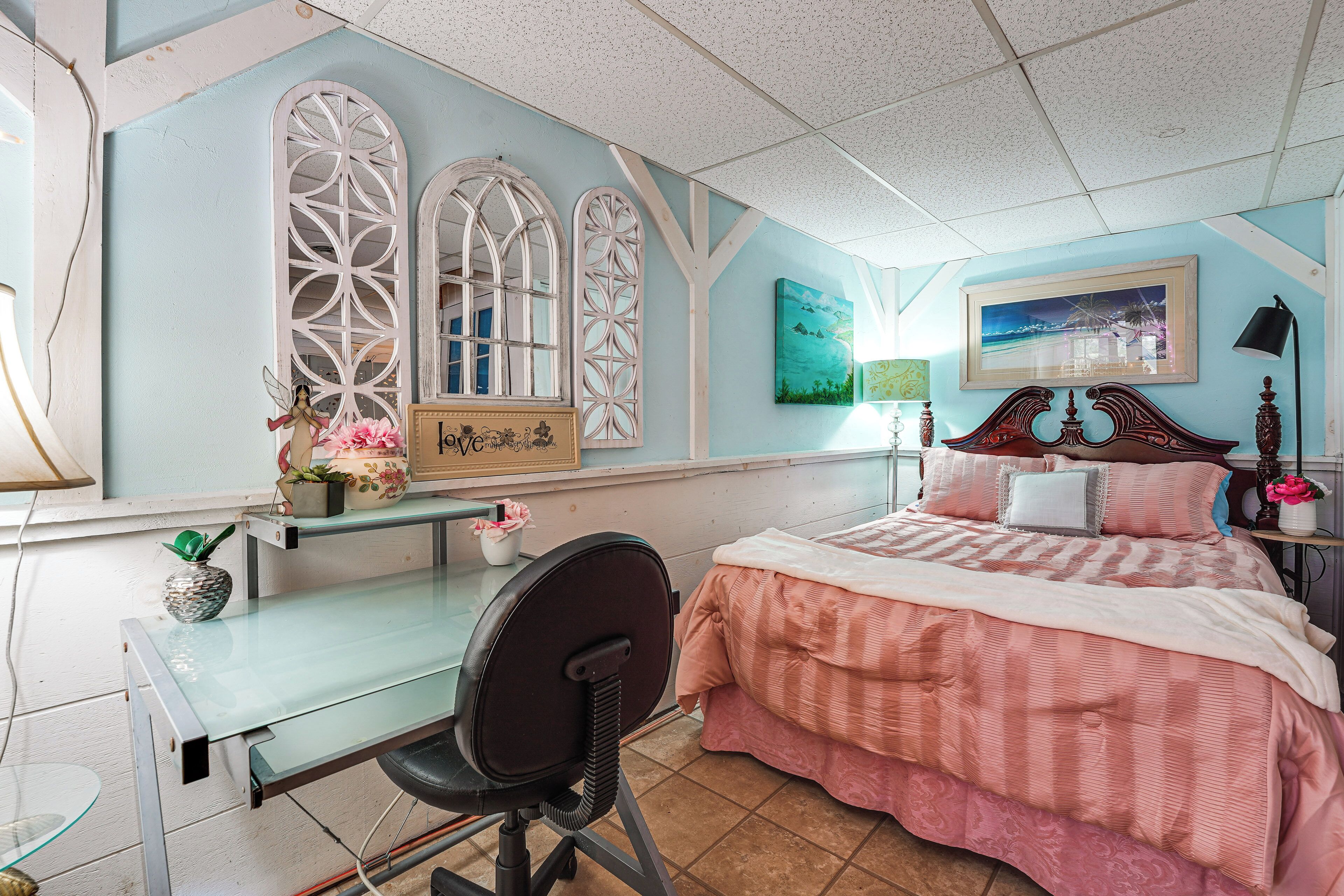 Un dormitorio con cama, escritorio, silla y objetos decorativos.
