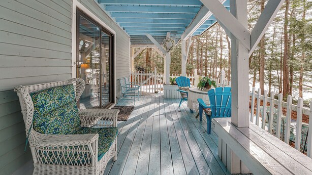 A covered porch with wicker furniture, a table, and chairs.