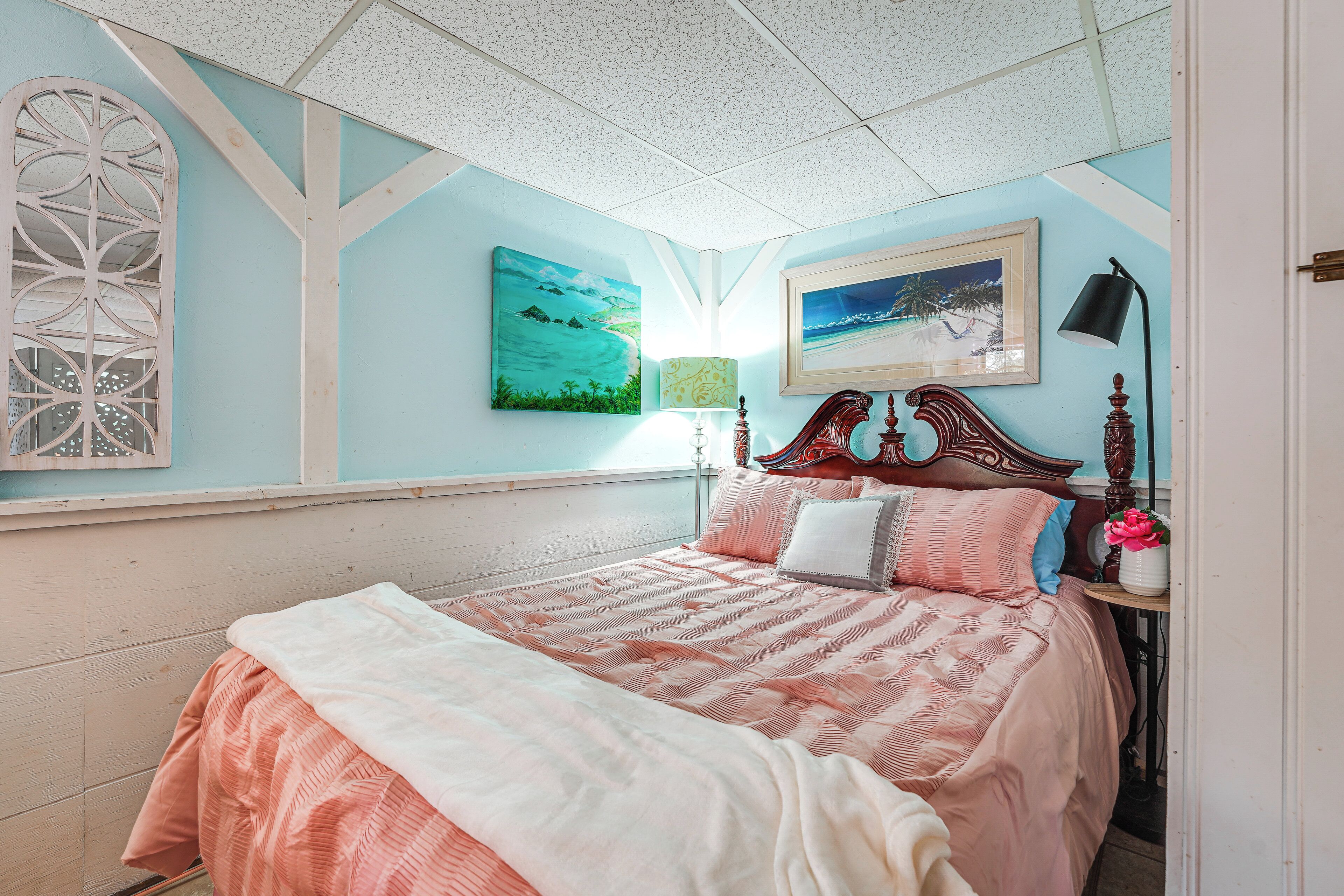 A bedroom with a bed, a nightstand, a lamp, and wall art.