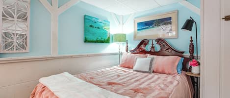 A bedroom with a bed, a nightstand, a lamp, and wall art.