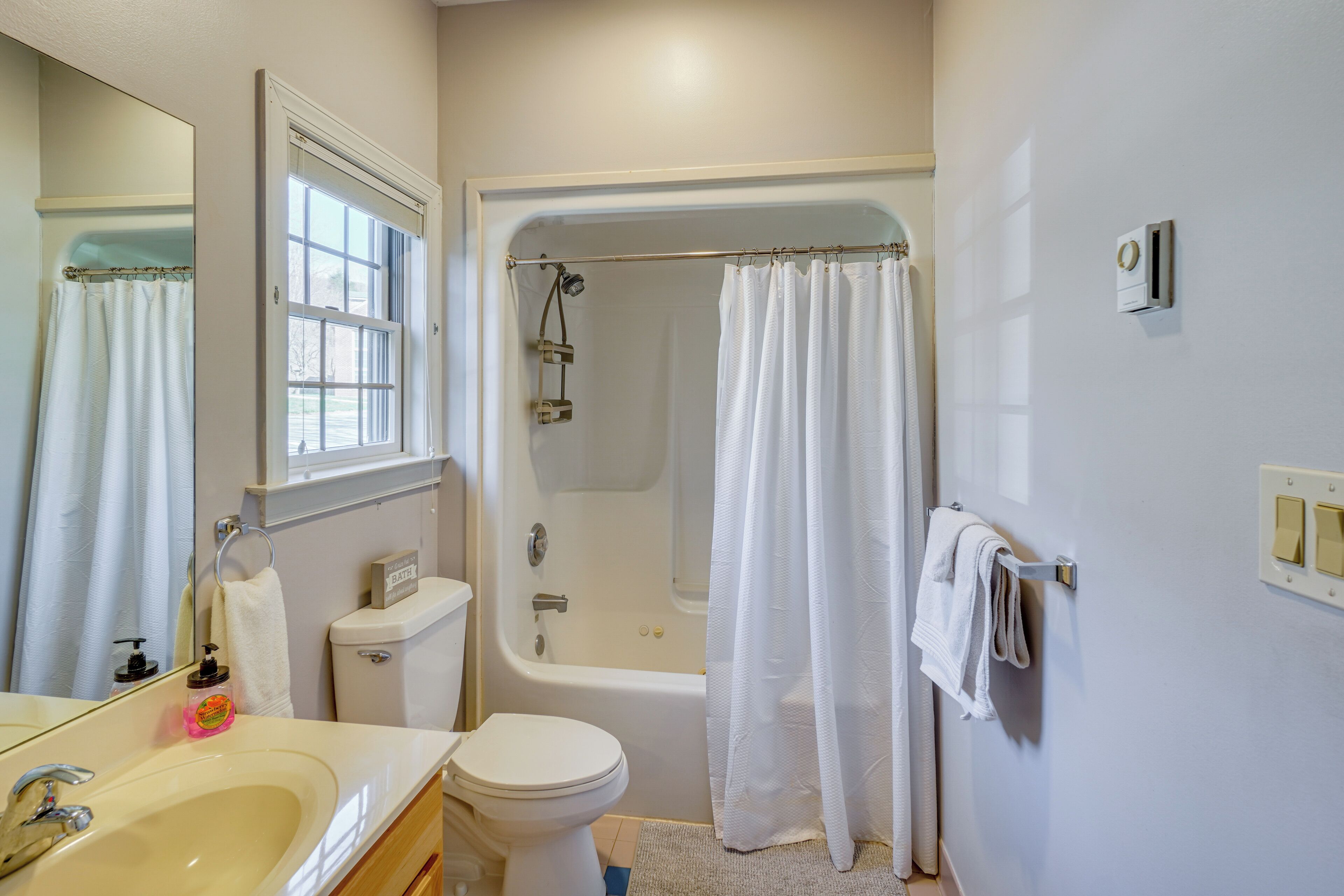 A bathroom with a bathtub, toilet, sink, and a window.